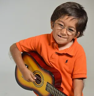 A young boy holding a guitar in front of him.